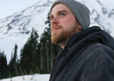 Man in beanie hat with Mt. Rainier in the background.